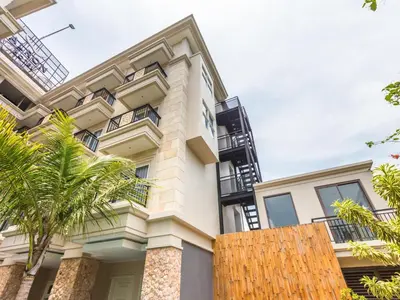 an exterior view of a house with palm trees at Alron Hotel Kuta in Kuta