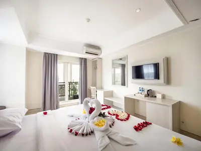 a hotel room with a bed with flowers on it at Alron Hotel Kuta in Kuta