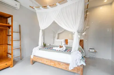 a bedroom with a canopy bed with a cat laying on it at Kubu Joglo Villa in Seminyak