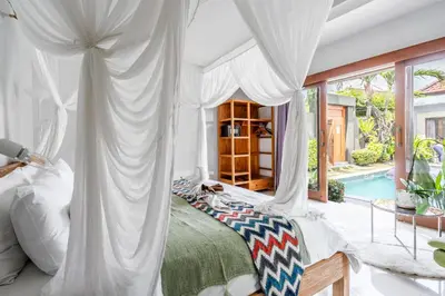 a bedroom with a canopy bed and a swimming pool at Kubu Joglo Villa in Seminyak