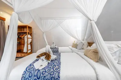 a bedroom with a white canopy bed with curtains at Kubu Joglo Villa in Seminyak