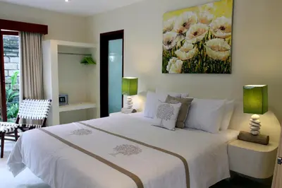 a bedroom with a white bed and a painting on the wall at Anyar Estate in Canggu