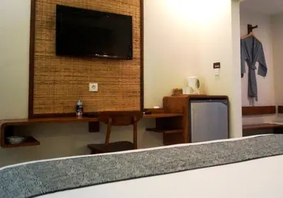 a room with a tv and a desk and a chair at Arana Suite in Legian