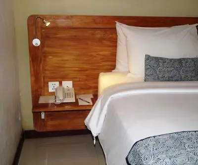 a bedroom with a bed and a phone on a nightstand at Arana Suite in Legian
