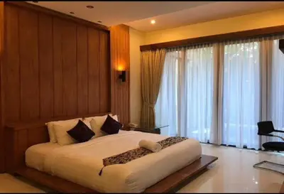 a bedroom with a large white bed and large windows at Alamanda Villa in Seminyak