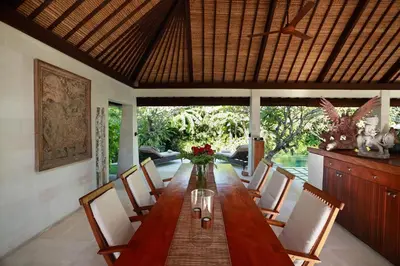 a dining room with a long wooden table and chairs at Villa Bali Asri in Seminyak