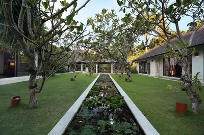 a garden with trees and a pond in front of a building at Villa Bali Asri in Seminyak