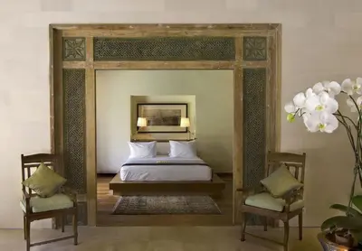 a bedroom with a bed and two chairs and a mirror at Villa Bali Asri in Seminyak