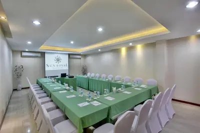 a conference room with a long table and white chairs at Sun Royal Hotel in Kuta