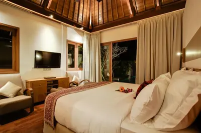 a bedroom with a large white bed and a television at KoenoKoeni Villa in Seminyak
