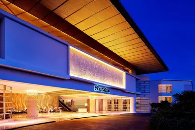 a building with a sign on the side of it at Sheraton Bali Kuta Resort in Kuta
