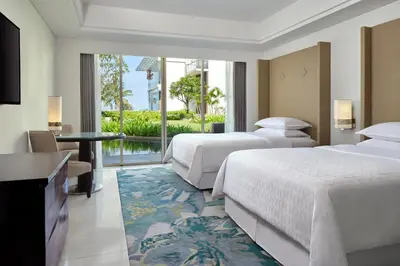 a hotel room with two beds and a view of a pool at Sheraton Bali Kuta Resort in Kuta