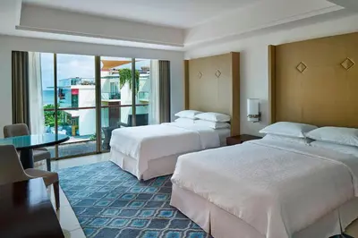 a hotel room with two beds and a balcony at Sheraton Bali Kuta Resort in Kuta