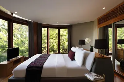 a bedroom with a large white bed with windows at Dacolina House in Jimbaran