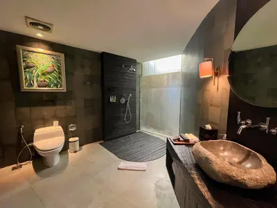 a bathroom with a shower and a toilet and a sink at Dacolina House in Jimbaran