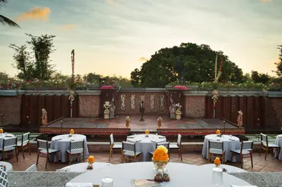 a patio with white tables and chairs and a table with flowers at AYANA Villas Bali in Jimbaran