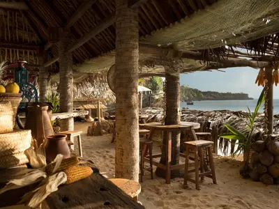 a restaurant on the beach with chairs and tables at AYANA Villas Bali in Jimbaran