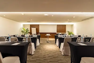 a conference room with tables and chairs and a screen at Bintang Kuta Hotel in Kuta