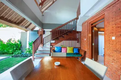 a dining room with a wooden table and a staircase at Mutiara Bali Boutique Resort & Villa in Seminyak