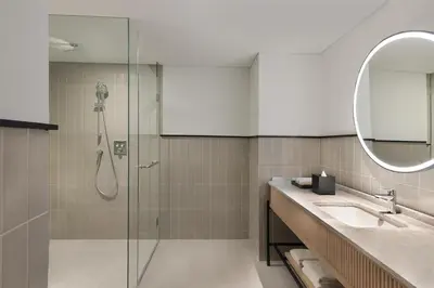 a bathroom with a shower and a sink and a mirror at Hilton Garden Inn Bali Nusa Dua in Nusa Dua