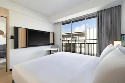 a bedroom with a large white bed and a flat screen tv at Hilton Garden Inn Bali Nusa Dua in Nusa Dua