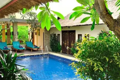 a villa with a swimming pool in front of a house at Sari Stay in Jimbaran