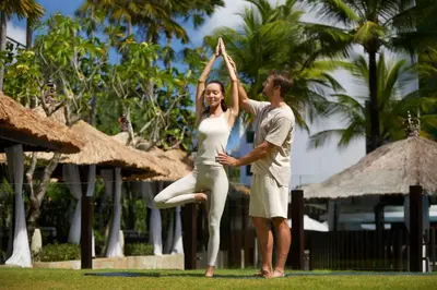 a man and a woman doing a yoga pose at The Stones Hotel - Legian Bali in Kuta