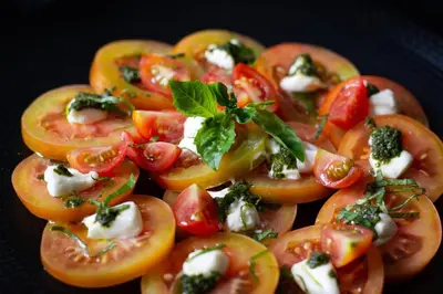 a plate of food with tomatoes and cheese and basil at The Stones Hotel - Legian Bali in Kuta