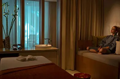 a man sitting on a bed in a hotel room at The Stones Hotel - Legian Bali in Kuta