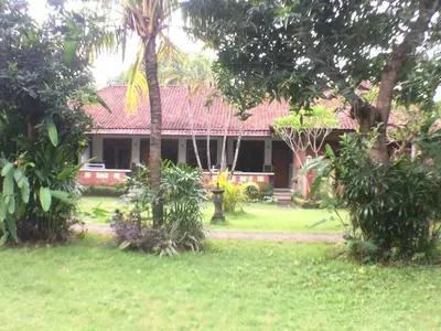 a house in the middle of a yard with trees at Mangga Bali Inn in Legian