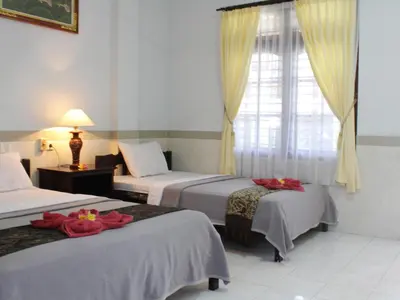 a hotel room with two beds and a window at Mangga Bali Inn in Legian