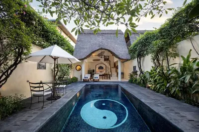 a swimming pool with a table and an umbrella at Impiana Private Villas Seminyak in Seminyak