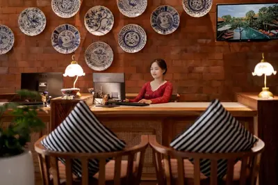a woman sitting at a counter with plates on the wall at Fourteen Roses Boutique Hotel, Kuta in Legian