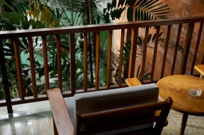 a balcony with a table and a wooden railing with plants at Fourteen Roses Boutique Hotel, Kuta in Legian