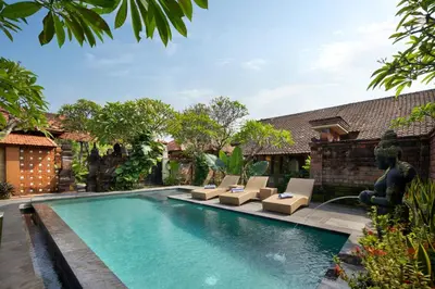 a swimming pool with lounge chairs and a fountain at Mahe Garden Kuta Villas by Kamara in Kuta