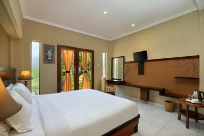 a bedroom with a large white bed and a television at Mahe Garden Kuta Villas by Kamara in Kuta