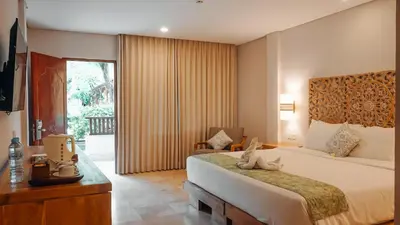 a hotel room with a bed and a television and a window at AlamKulkul Boutique Resort in Kuta