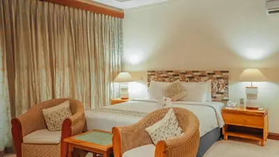 a bedroom with a large bed and two chairs at AlamKulkul Boutique Resort in Kuta