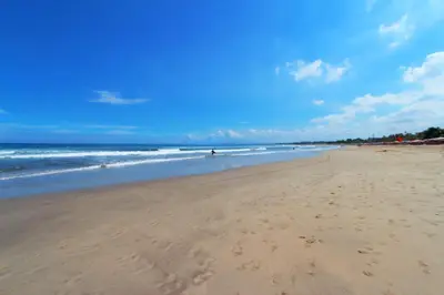 a beach with footprints in the sand and the ocean at AlamKulkul Boutique Resort in Kuta