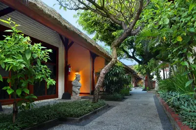 a building with a tree next to a sidewalk at AlamKulkul Boutique Resort in Kuta