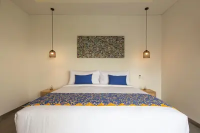 a bedroom with a large white bed with blue pillows at Villa Arif in Seminyak