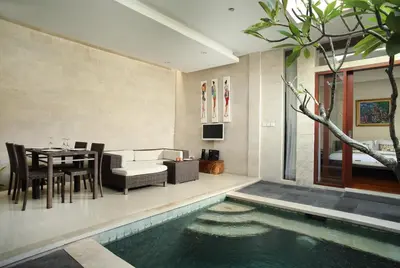 a living room with a table and a swimming pool at Daluman Villas in Seminyak