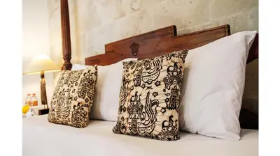 a bed with two pillows on top of it at Sunhouse Guesthouse in Sanur