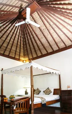 a bedroom with a canopy bed with a ceiling fan at Sunhouse Guesthouse in Sanur