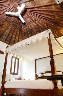 a bedroom with a bed with a ceiling fan at Sunhouse Guesthouse in Sanur