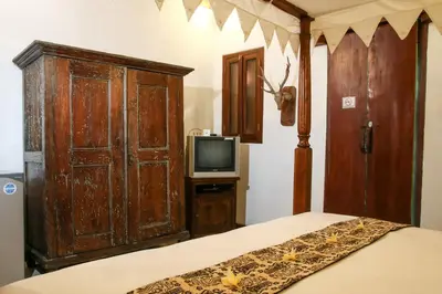 a bedroom with a bed and a wooden cabinet and a tv at Sunhouse Guesthouse in Sanur