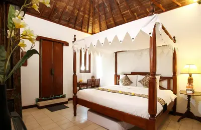 a bedroom with a bed with a canopy at Sunhouse Guesthouse in Sanur
