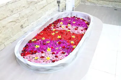 a large bath tub filled with flowers in front of a fireplace at Villa Latour in Seminyak