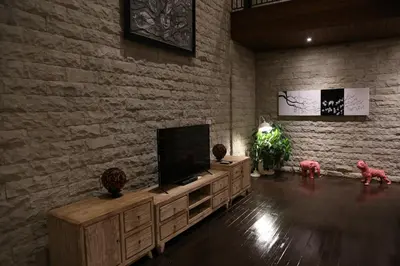 a living room with a tv and a brick wall at Villa Latour in Seminyak