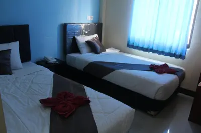 two beds in a bedroom with blue walls at Asher Bali Transit in Kuta